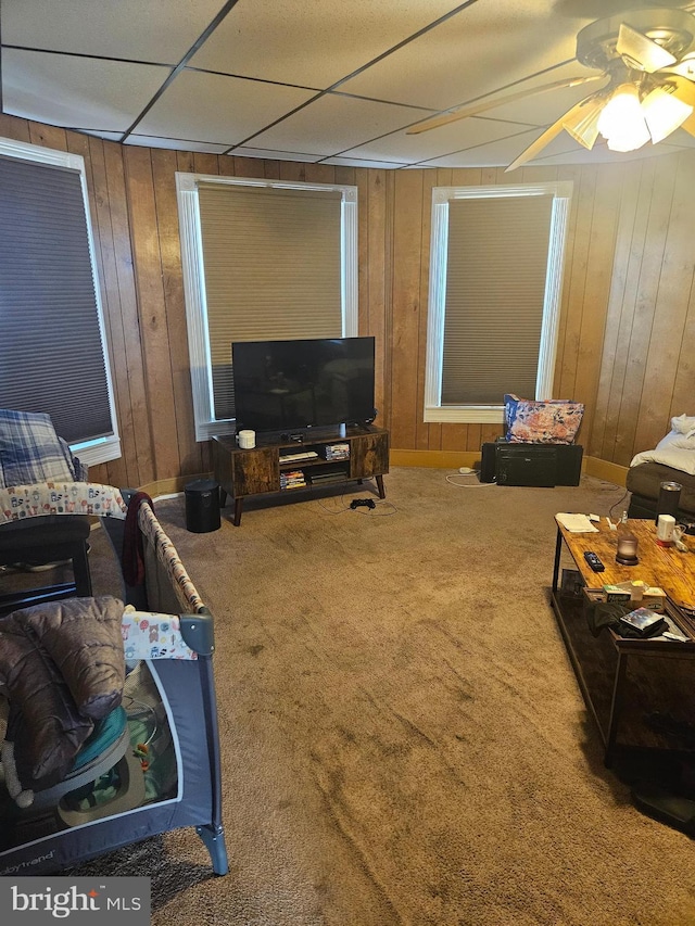 carpeted living area featuring ceiling fan and wooden walls