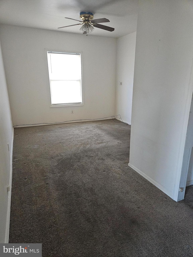 carpeted empty room featuring ceiling fan and baseboards