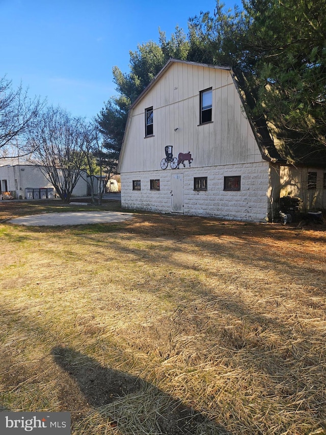 view of home's exterior featuring a barn, an outdoor structure, a lawn, and a gambrel roof