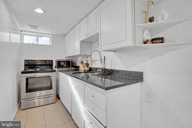 kitchen featuring light tile patterned floors, white cabinets, dark stone countertops, stainless steel appliances, and a sink