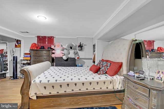 bedroom featuring visible vents, wood finished floors, and ornamental molding