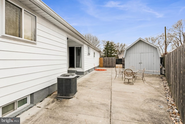 view of patio / terrace with a fenced backyard, a storage unit, cooling unit, and an outbuilding