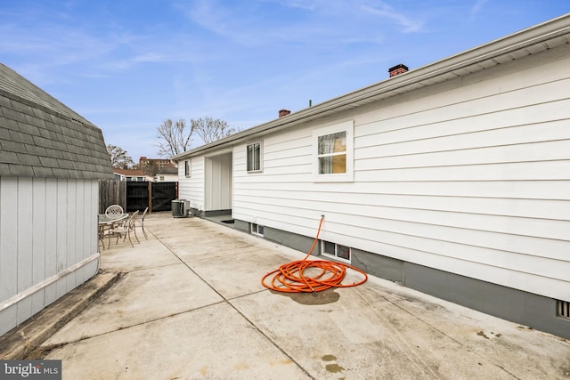 exterior space with a chimney, fence, an outdoor structure, a patio area, and central AC