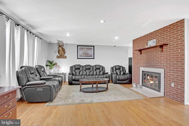 living room featuring recessed lighting, a brick fireplace, and wood finished floors