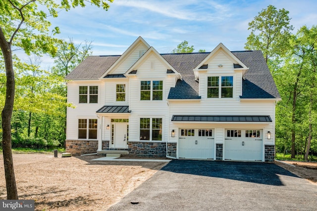 view of front of house with stone siding, metal roof, aphalt driveway, roof with shingles, and a standing seam roof