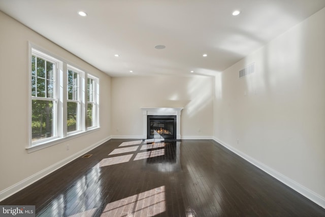 living room featuring baseboards, visible vents, a glass covered fireplace, hardwood / wood-style floors, and recessed lighting