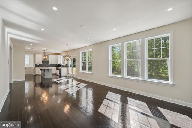 living room featuring dark wood-style flooring, a wealth of natural light, and a notable chandelier