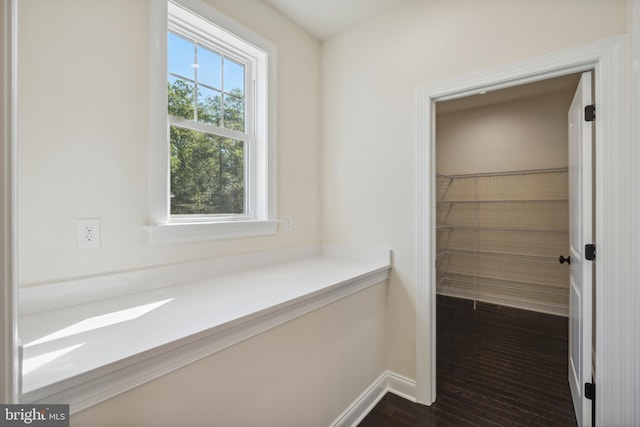 hallway featuring baseboards and dark wood-type flooring