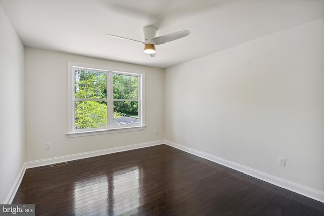 spare room with dark wood-type flooring, visible vents, baseboards, and a ceiling fan