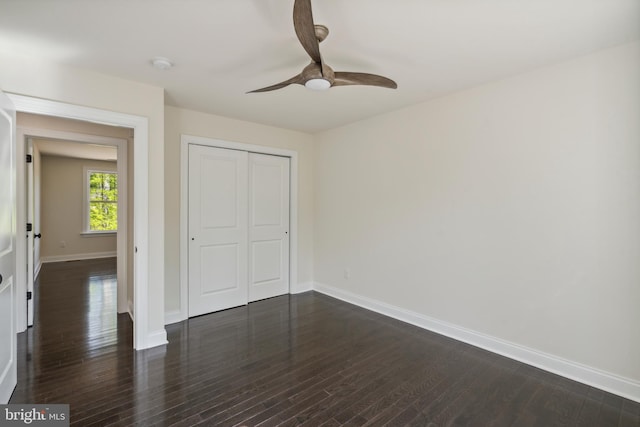 unfurnished bedroom featuring a closet, dark wood finished floors, baseboards, and ceiling fan