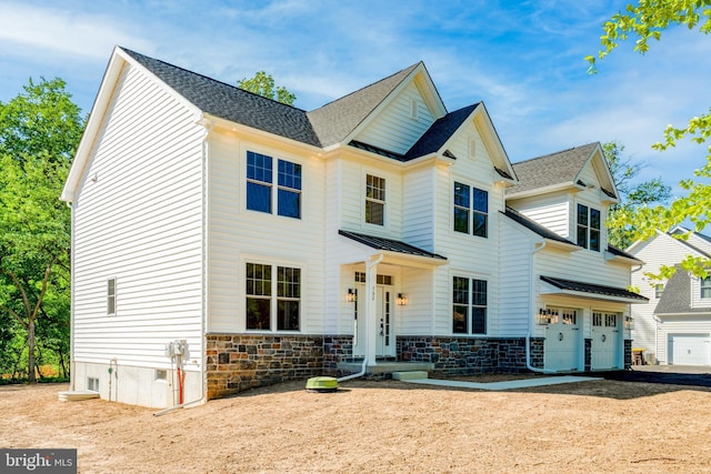 view of front of property featuring metal roof, stone siding, a standing seam roof, and an attached garage