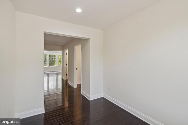 spare room featuring dark wood-style flooring, recessed lighting, and baseboards