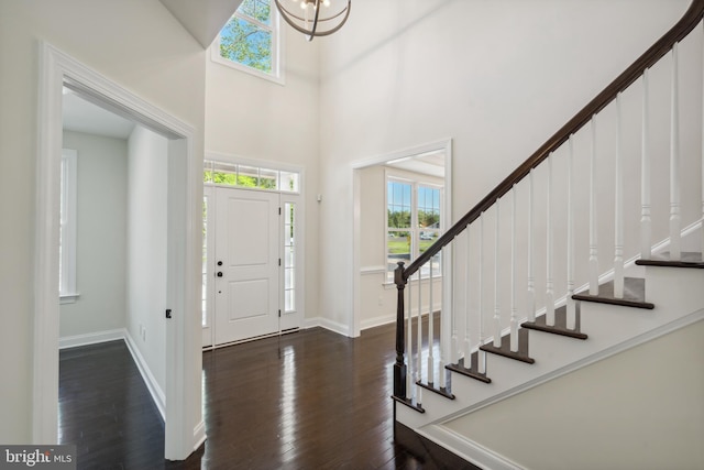 foyer featuring dark wood-style floors, stairway, a towering ceiling, and baseboards