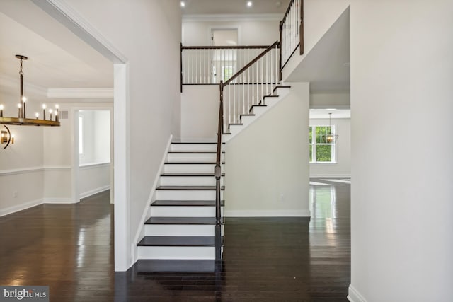 stairs featuring crown molding, baseboards, a notable chandelier, and wood finished floors