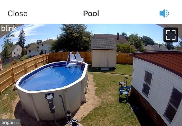 view of swimming pool with a fenced in pool, a fenced backyard, a yard, an outdoor structure, and a storage unit