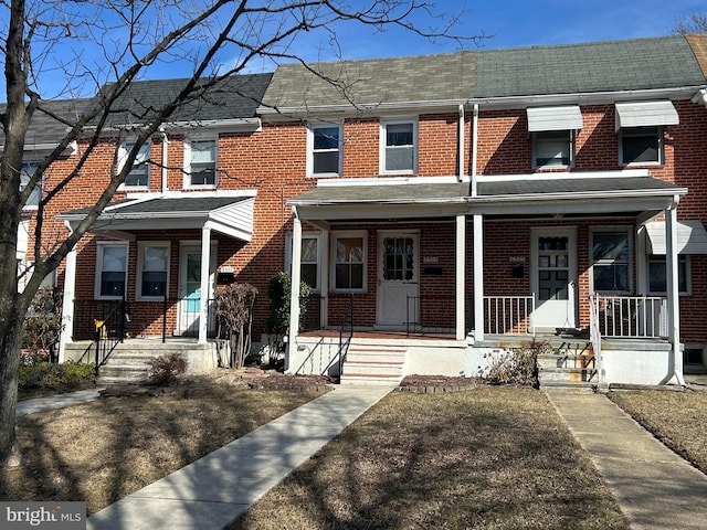 multi unit property with a porch and brick siding