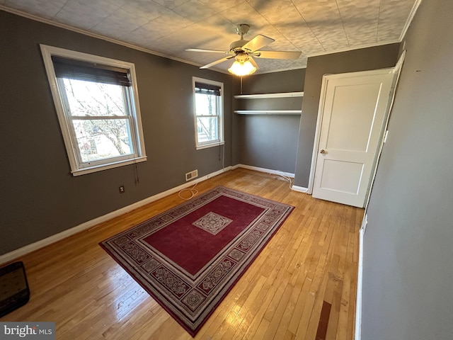 unfurnished bedroom with light wood-style floors, visible vents, ornamental molding, and baseboards