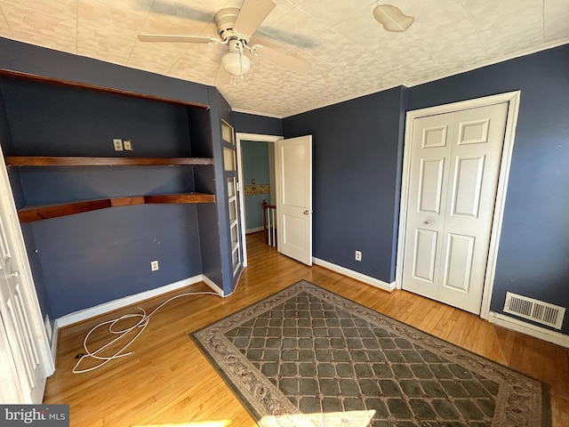 unfurnished bedroom featuring ceiling fan, wood finished floors, visible vents, and baseboards