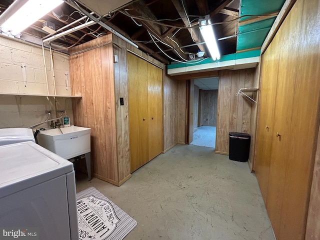 laundry area with wooden walls, laundry area, a sink, independent washer and dryer, and concrete block wall