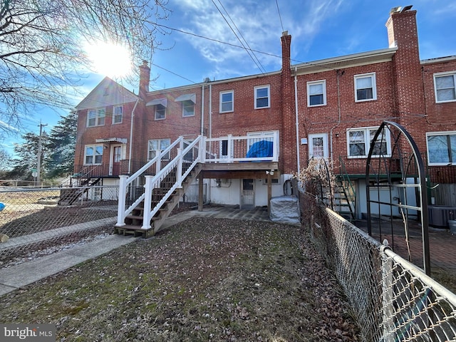 rear view of house featuring a patio area, brick siding, fence, and stairway