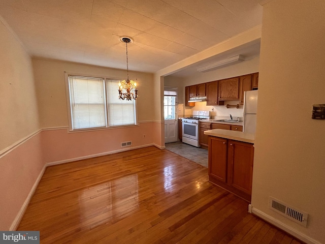 kitchen featuring dark wood finished floors, white appliances, a sink, and visible vents