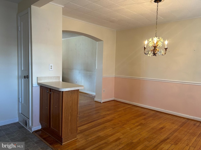 kitchen featuring dark wood-style floors, arched walkways, brown cabinets, and light countertops