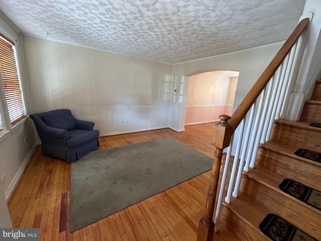 living area with stairs, arched walkways, baseboards, and hardwood / wood-style flooring