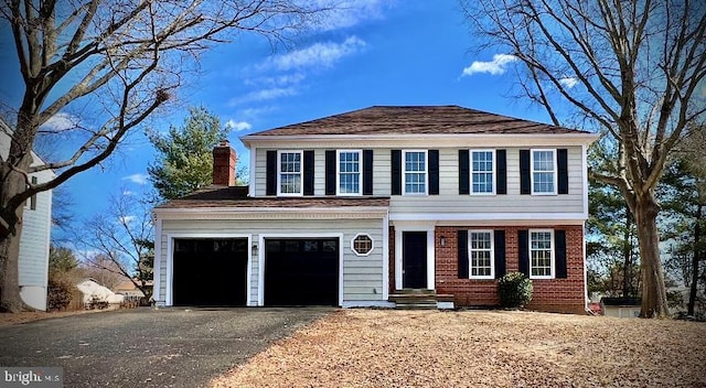 view of front of house featuring driveway, entry steps, a chimney, and brick siding