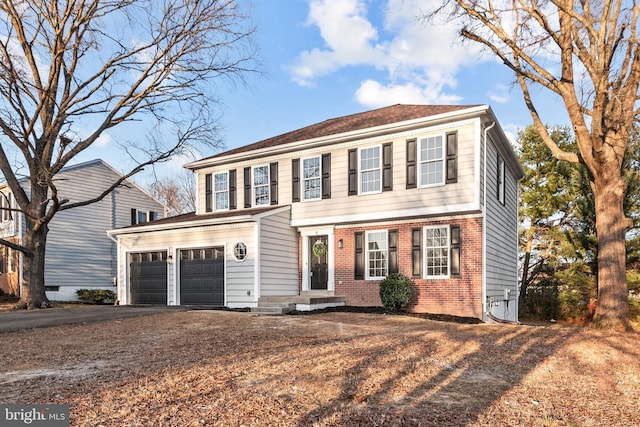 colonial-style house featuring driveway and brick siding