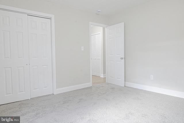 unfurnished bedroom featuring carpet floors, baseboards, and a closet