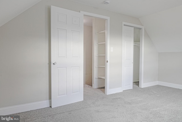 interior space featuring carpet, baseboards, and vaulted ceiling