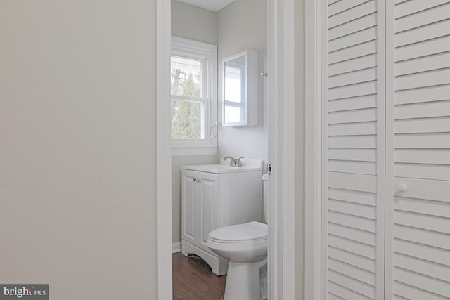 half bathroom with vanity, toilet, and wood finished floors