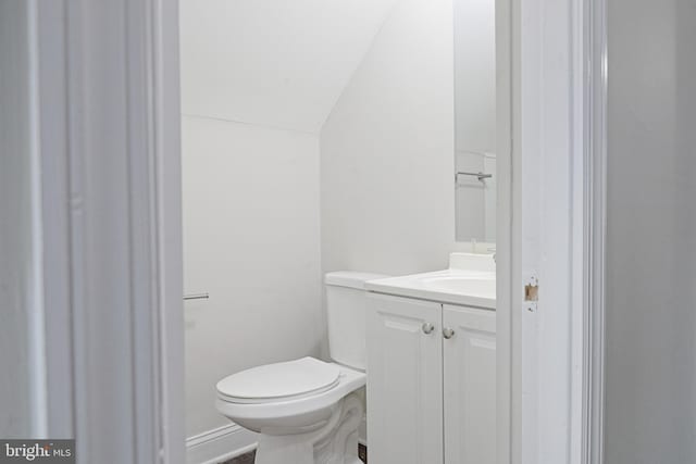 bathroom featuring toilet, vaulted ceiling, and vanity