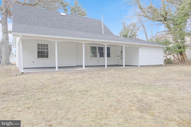 rear view of property featuring a patio area, a lawn, and roof with shingles