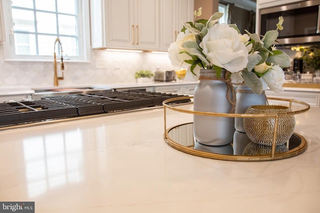 details with a sink, white cabinetry, stainless steel microwave, and backsplash