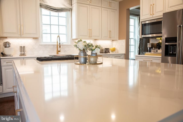 kitchen with appliances with stainless steel finishes, light countertops, decorative backsplash, and white cabinetry