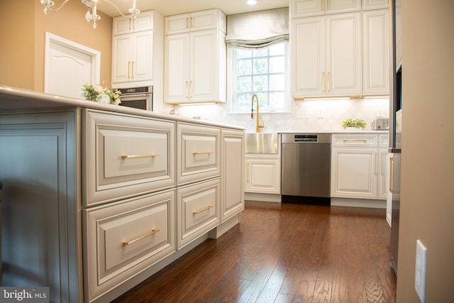 kitchen with stainless steel appliances, dark wood-type flooring, a sink, white cabinets, and light countertops