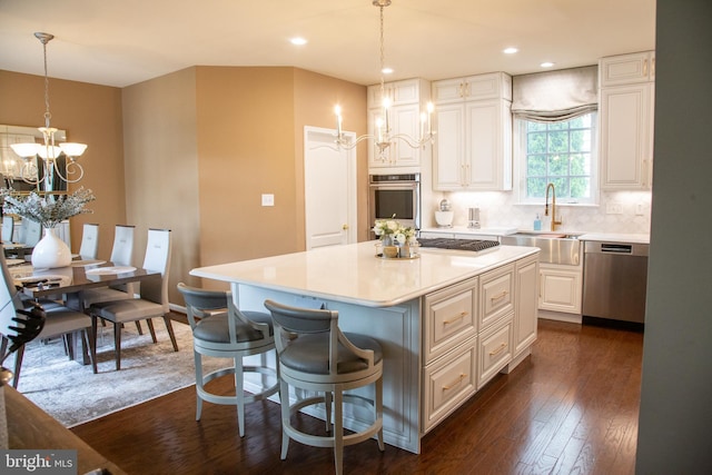 kitchen with a kitchen island, appliances with stainless steel finishes, dark wood-style flooring, a chandelier, and a sink