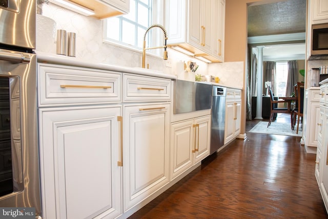 kitchen featuring stainless steel appliances, light countertops, dark wood-type flooring, and backsplash