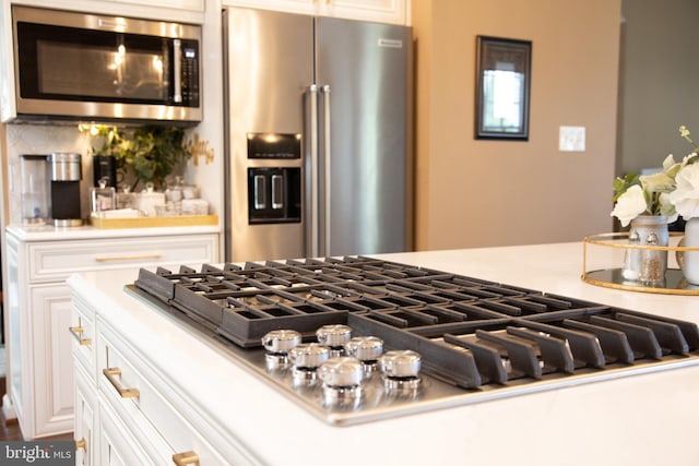 details with stainless steel appliances, white cabinets, and light countertops