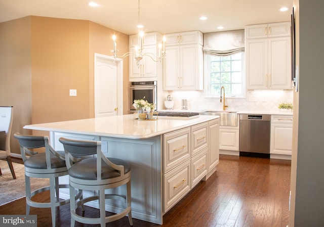 kitchen with a center island, a kitchen breakfast bar, dark wood-style floors, stainless steel appliances, and a sink