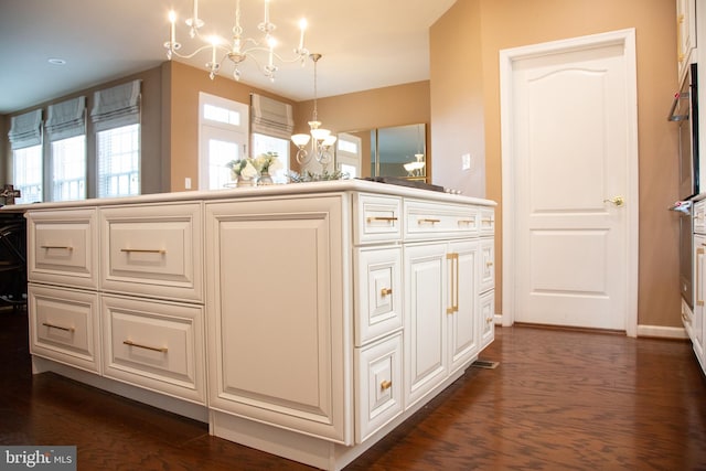 interior space with pendant lighting, a notable chandelier, dark wood-type flooring, white cabinets, and baseboards