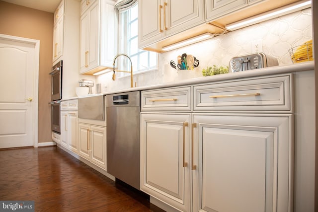 kitchen featuring a sink, dark wood finished floors, stainless steel appliances, and light countertops