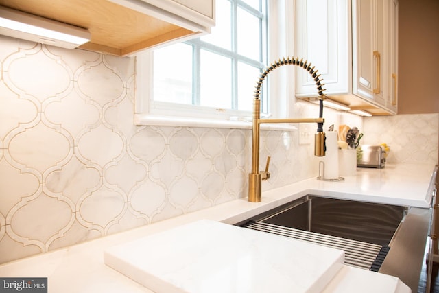 details featuring a sink, light countertops, and backsplash