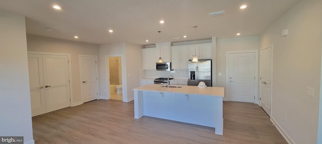 kitchen featuring wood finished floors, visible vents, white cabinets, appliances with stainless steel finishes, and an island with sink