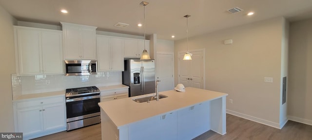 kitchen featuring stainless steel appliances, visible vents, backsplash, a kitchen island with sink, and a sink