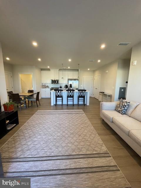 living area with wood finished floors, visible vents, and recessed lighting