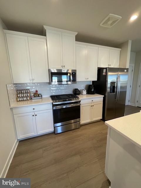 kitchen with tasteful backsplash, white cabinetry, appliances with stainless steel finishes, and light countertops