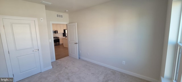 unfurnished bedroom featuring light carpet, baseboards, visible vents, and freestanding refrigerator