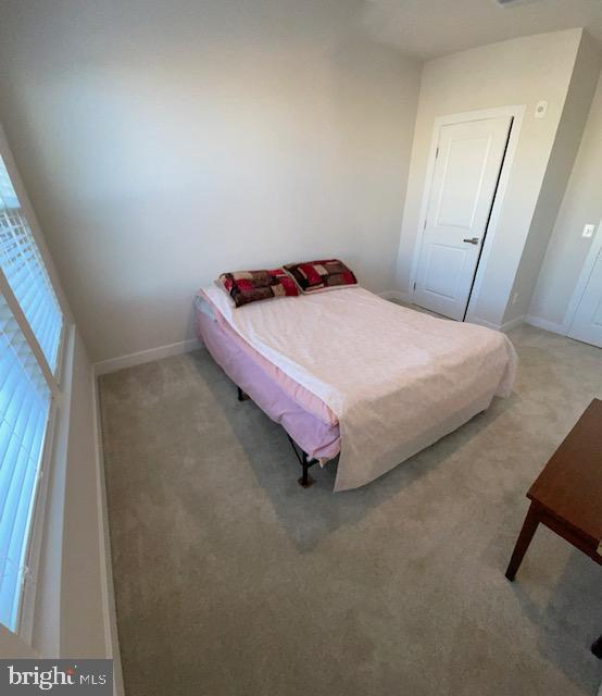 bedroom featuring light carpet and baseboards